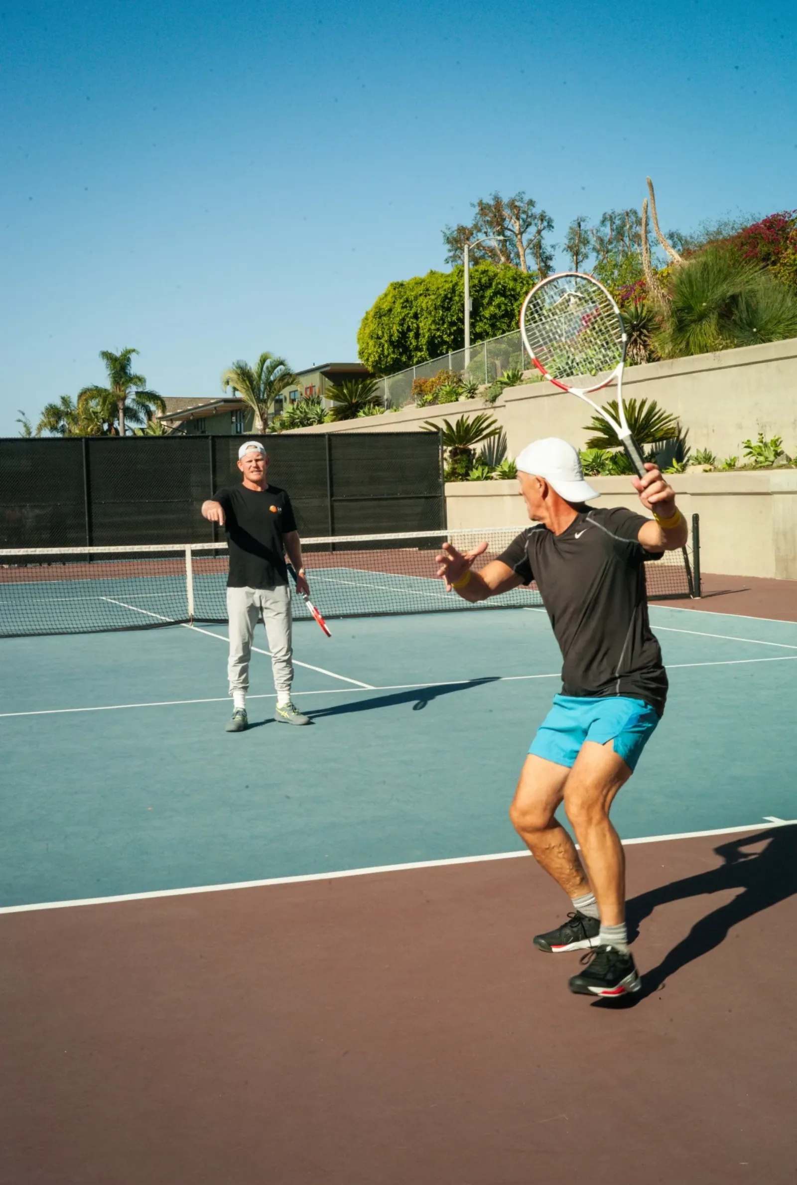 Two adult players in a competitive rally on an outdoor court