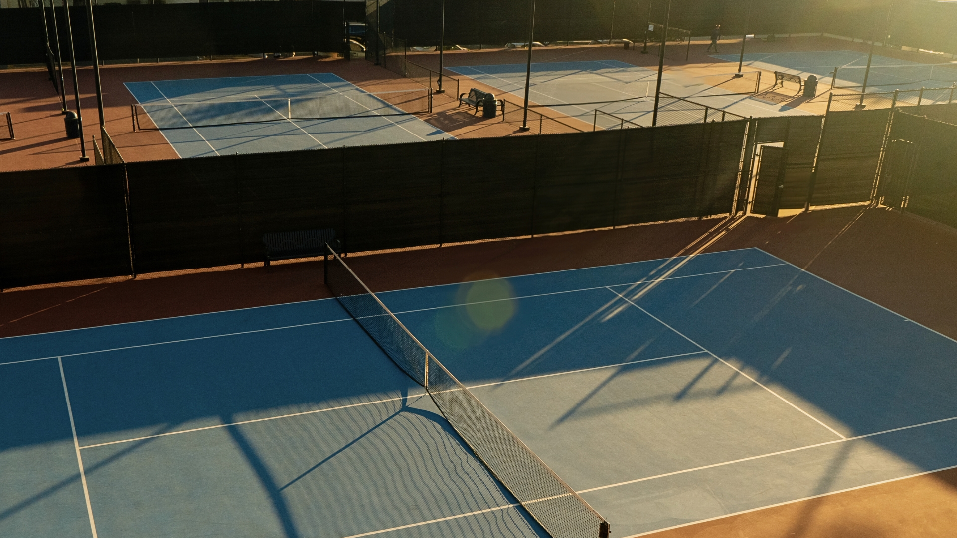 Sunlit blue hard courts — clarity of line and surface for focused training