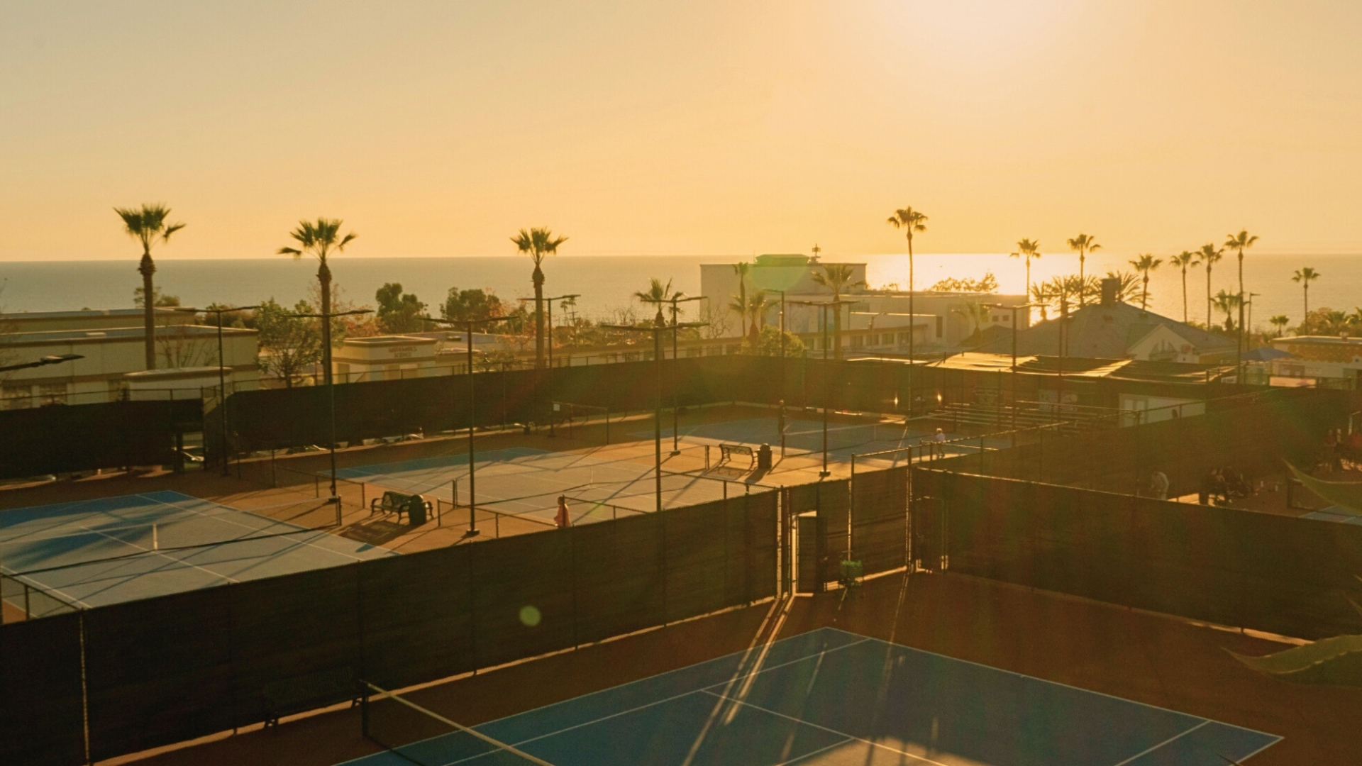 Coastal tennis courts at sunset with the Pacific horizon beyond Laguna Beach