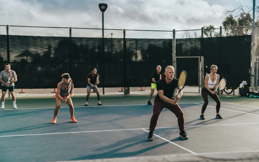 Adults in ready position across a full court under the lights