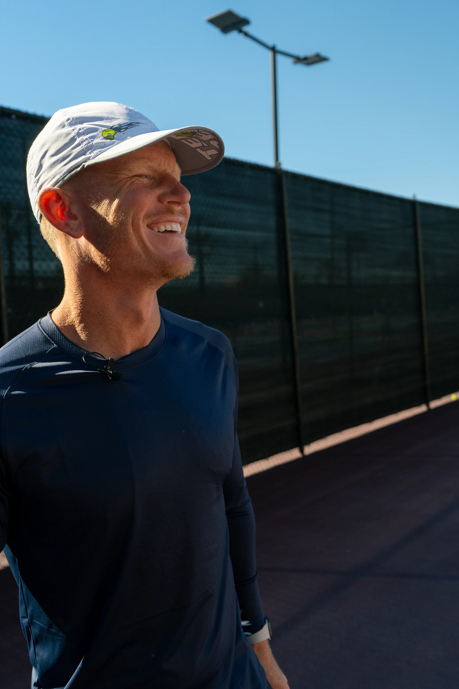 Andrew Mateljan smiling on an outdoor tennis court