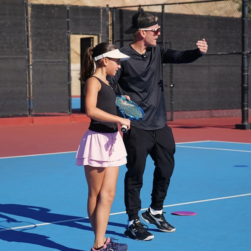 Coach Andrew instructing a junior player during a private lesson on a blue court