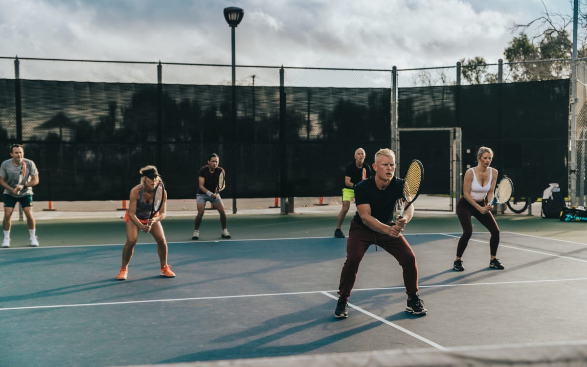 Adults spread across the court in ready position during an evening drill
